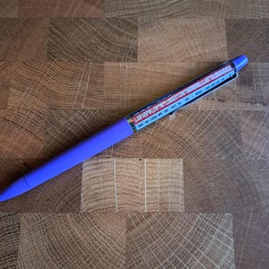 Op de afbeelding: Een paarse pen met een wit label waarop "LLME AIR PILLOW WITH THE ROGER KENT/ROLLING STONES" staat.
