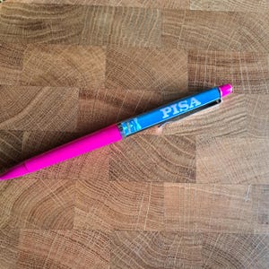 May include: A pink and blue pen with the word "PISA" printed on the blue part of the pen.