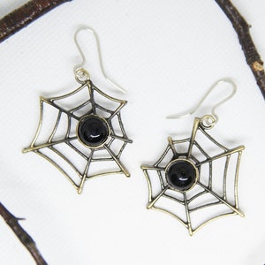 Puede incluir: Un par de pendientes de telaraña de oro y negro con detalles de piedras preciosas negras.