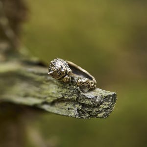 Op de afbeelding: Een zilveren ring met een wolfskopontwerp. De ring ligt op een stuk verweerd hout.