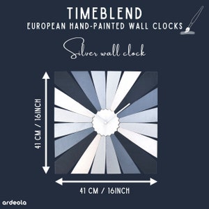 May include: A silver wall clock with a white face and black hands. The clock is made of wood and has a unique design with shades of blue and white. The clock is 41 cm in diameter.
