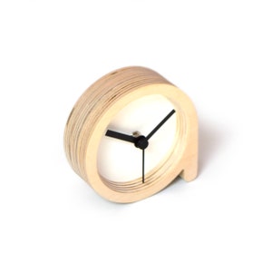 May include: A wooden clock with black hands and a white face. The clock is shaped like a circle with a small, curved tail.