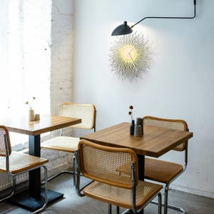 Liten väggklocka i guldfärgad solstråle, modern skulptural accentdekor