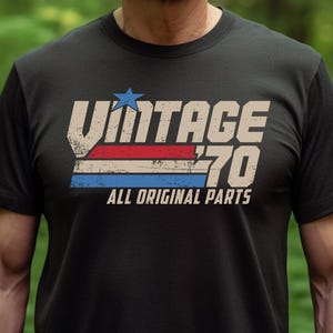 May include: Black t-shirt with a vintage-style graphic that says "Vintage 70 All Original Parts" in white, red, and blue.