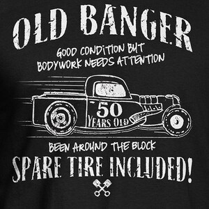 K&ouml;nnte beinhalten: Ein schwarz-wei&szlig;es Grafikdesign eines Oldtimer-Hot-Rods mit dem Text "OLD BANGER" und "GOOD CONDITION BUT BODYWORK NEEDS ATTENTION". Das Auto hat ein Schild mit der Aufschrift "50 YEARS OLD" an der Seite und den Text "BEEN AROUND THE BLOCK SPARE TIRE INCLUDED!"