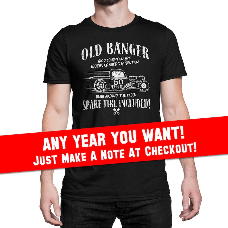 K&ouml;nnte beinhalten: Schwarzes T-Shirt mit einer wei&szlig;en Grafik eines Oldtimer-Hot-Rods mit dem Text "Old Banger" und "Spare Tire Included!" Die Grafik enth&auml;lt auch den Text "Good Condition But Bodywork Needs Attention" und "50 Years Old". Der Text "Any Year You Want! Just Make A Note At Checkout!" ist in Rot auf einem wei&szlig;en Banner gedruckt.