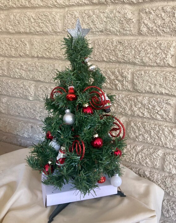 Christmas tree for cemetery with red Santa’s and red balls . This is a mini tree of 12”