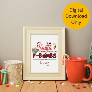 May include: A framed print with the text "Dear Santa, Sorry for all the F-Bombs, 2022 Was Crazy." The print has a Santa hat and gift box graphics. A red mug and a candy cane are on the table. The image is labeled "Digital Download Only."