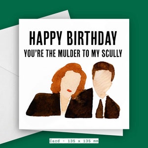 May include: A white card with a watercolour illustration of two people, a woman with red hair and a man with brown hair. The text on the card reads "Happy Birthday You're the Mulder to my Scully". The card is 135 mm by 135 mm.