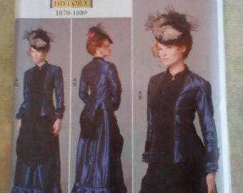 May include: Butterick B6305 sewing pattern for a historical costume from 1870-1880. The pattern features a woman in a dark blue, long-sleeved dress with a matching jacket and a hat with a veil. The pattern includes multiple views of the costume.