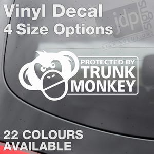 May include: White vinyl decal featuring a monkey face and the text "PROTECTED BY TRUNK MONKEY." The decal also includes the text "Vinyl Decal, 4 Size Options, 22 Colours Available."