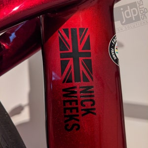 K&ouml;nnte beinhalten: Ein roter Fahrradrahmen mit einer schwarzen Union Jack Flagge und dem Aufdruck "NICK WEEKS".