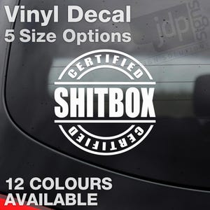 May include: White vinyl decal with the text "Vinyl Decal" and "5 Size Options" at the top. The center features a circular design with "CERTIFIED" around the top and bottom, and "SHITBOX" in the middle. The bottom text reads "12 COLOURS AVAILABLE".