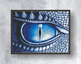 May include: A framed close-up of a dragon's eye, rendered in shades of blue. The eye features a detailed iris and pupil, surrounded by textured scales. The artwork is framed in a dark brown border, creating a striking visual.