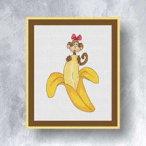 Könnte beinhalten: Ein Kreuzstichmuster eines Affen mit einer roten Schleife, der aus einer gelben Bananenschale schaut.