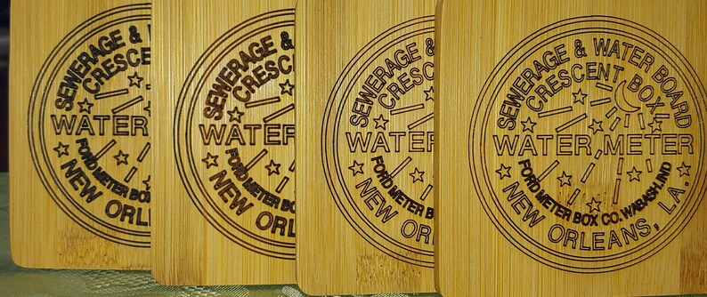 May include: Four wooden coasters with a laser-engraved design featuring the text "SEWERAGE & CRESCENT WATER" and "FORD METER BOX CO. WABASH, LA."