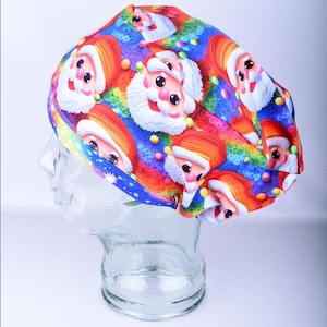 May include: A colorful Santa Claus print scrub cap. The cap features a repeating pattern of Santa faces with orange hats and white beards on a rainbow background. The cap is designed to fit over the head.