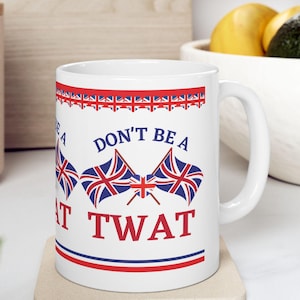 May include: White ceramic mug with the text "DON'T BE A TWAT" in red and black, along with Union Jack flag graphics. The mug has a red and blue border design and is sitting on a neutral-colored coaster.