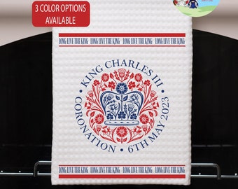 May include: A white tea towel with a red, blue, and white design featuring a crown and the text "King Charles III Coronation 6th May 2023". The text "Long Live The King" is repeated around the border.