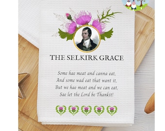 May include: A white tea towel with a printed image of a man and a poem. The poem is titled "The Selkirk Grace" and reads: "Some hae meat and canna eat, And some wad eat that want it, But we hae meat and we can eat, Sae let the Lord be Thankit!"