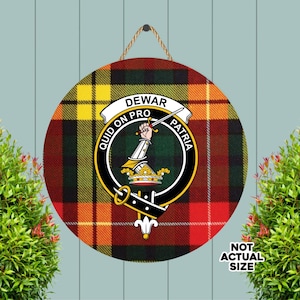 Puede incluir: Cartel redondo de madera con un fondo de cuadros escoceses en rojo, amarillo y verde. El cartel presenta un escudo con las palabras "DEWAR", "QUID ON PRO" y "PATRIA". Se adjunta una cuerda para colgarlo. El texto "NOT ACTUAL SIZE" está en la esquina inferior derecha.