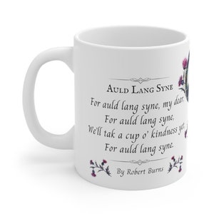 May include: White ceramic mug with a black and white print of the lyrics to the song "Auld Lang Syne" by Robert Burns. The mug is decorated with a floral design featuring purple and green thistles.