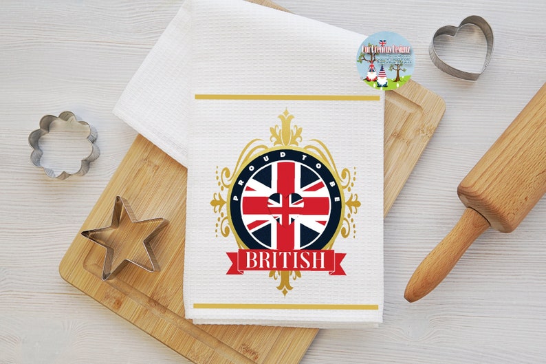 May include: White kitchen towel with a gold and blue design featuring the Union Jack flag and the text "Proud to be British".