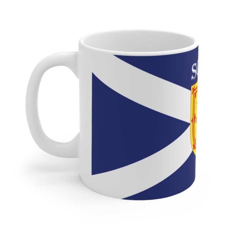 May include: White ceramic mug with a blue and white Scottish flag design. The flag features a white diagonal cross on a blue background with a yellow and red Scottish coat of arms in the upper right corner.
