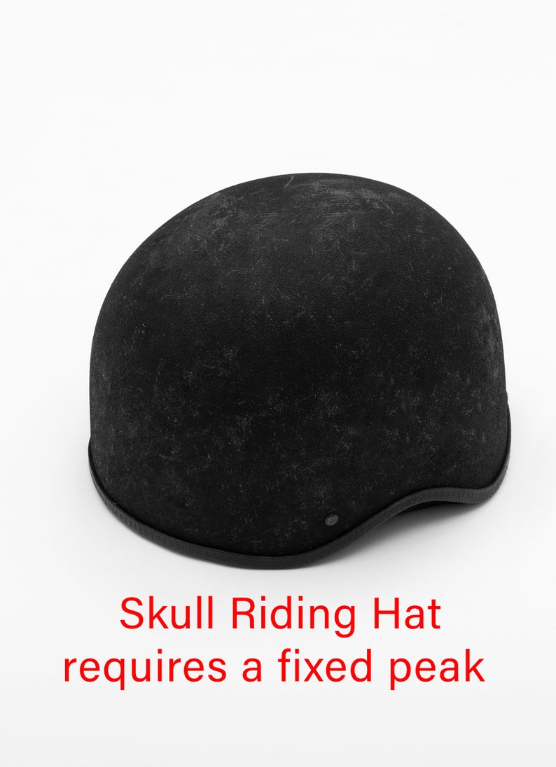 K&ouml;nnte beinhalten: Ein schwarzer Skull-Reithut mit festem Schirm. Der Hut hat eine Kuppelform mit strukturierter Oberfl&auml;che und dunklem Besatz am unteren Rand. Der Text "Skull Riding Hat requires a fixed peak" ist rot.