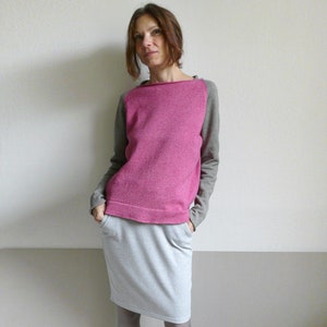 May include: A woman wearing a pink and gray sweater with a gray skirt and pink shoes.