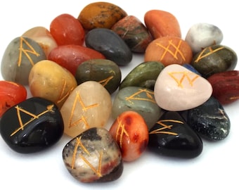 May include: A collection of 20 tumbled stones with gold runes inscribed on them. The stones are in various colors, including red, orange, yellow, green, brown, black, and white.