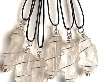May include: Seven clear quartz crystal pendants wrapped in silver wire, each on a black cord necklace.