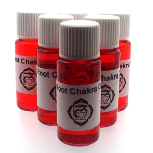 Könnte beinhalten: Sechs kleine rote Glasflaschen mit weißen Deckeln und Etiketten. Die Etiketten zeigen ein schwarzes Symbol und den Text "Root Chakra Oil".