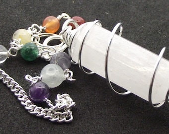 May include: A white crystal pendulum with a silver wire wrapped around it. The pendulum is attached to a silver chain with seven beads in various colors, including clear, yellow, green, orange, purple, and light green.