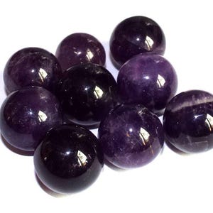 May include: A group of ten amethyst spheres, each with a smooth, polished surface. The spheres are various shades of purple, ranging from light to dark.