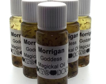 May include: A collection of small glass bottles filled with a light brown liquid and herbs. Each bottle has a white cap and a label that reads "Morrigan Goddess Magickal Oil". The bottles are arranged in a group.