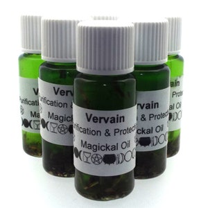 Puede incluir: Cinco pequeñas botellas de vidrio verde con tapas blancas. Cada botella tiene una etiqueta blanca con el texto "Vervain, Purification & Protection, Magickal Oil" y varios símbolos. Las botellas están llenas de un líquido verde oscuro.