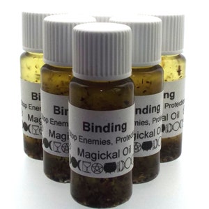 May include: Six small glass bottles filled with a dark liquid and herbs. Each bottle has a white label with black text that reads "Binding Stop Enemies, Protect Magickal Oil".