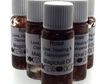 May include: Six small glass bottles filled with a red liquid and rose petals. Each bottle has a white label with the words "Rose, Love, Healing & Clairvoyance, Magickal Oil".