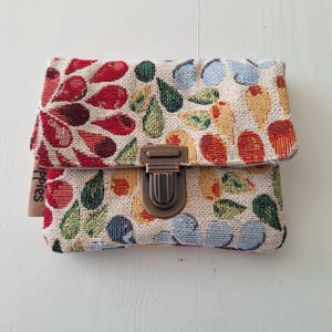 Mini carteira alegre da Gobelin com um pitoresco padrão de flores. Compacto e prático, cabe facilmente no bolso ou na bolsa pequena.