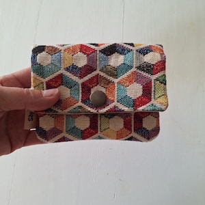 Mini portefeuille coloré en gobelin robuste et inaltérable avec des hexagones. Compact et pratique, il se glisse facilement dans votre poche ou votre petit sac.