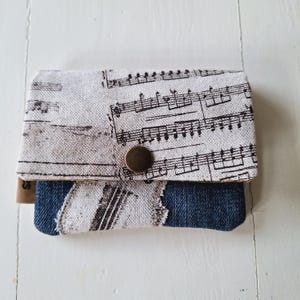 Einzigartige Geldbörse für den Musikliebhaber. Musikalischer Print kombiniert mit Denim-Jeans für einen coolen Touch. Karten und Münzen.