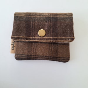 Elegante mini portafoglio realizzato in tessuto misto lana con motivo a quadri. Design compatto e pratico, sta facilmente in tasca o in una piccola borsa.