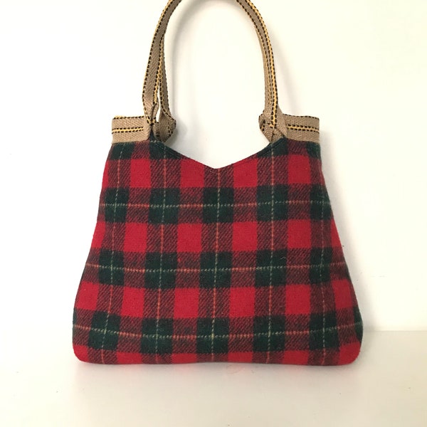 Sac bandoulière en tartan de laine rouge vert, entièrement doublé, poche intérieure avec fermeture éclair et poche téléphone. Se ferme avec un bouton pression aimanté.