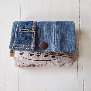 Geldbörse für den Musikliebhaber. Musikalischer Print kombiniert mit Denim-Jeans für einen coolen Touch. Platz für Karten und Münzen.