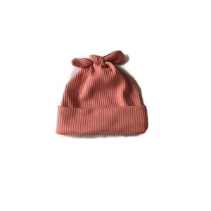 Può includere: Un berretto in maglia a coste color corallo con bordo risvoltato e fiocco decorativo sulla parte superiore. Il cappello è realizzato in un materiale morbido e strutturato ed è adatto a neonati e bambini piccoli.