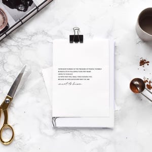 May include: A white card with black text on a marble surface. The text reads: "Never rob yourself of the treasure of finding yourself. Be resolute in following your own heart. Listen to your gut. Go with that still small voice nudging you. Because no one else knows who you are meant to become."