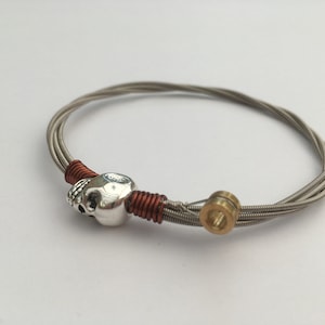 Pulsera de cuerdas de bajo recicladas, con una cuenta de calavera y alambre de cobre. Regalo unisex único para guitarristas.