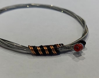 Manchester Bee: Recycled Guitar String Bracelet, styled with black and bronze wire. Unisex Unique Guitarist Gift