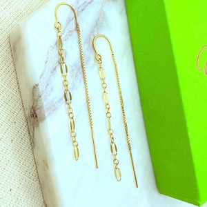 May include: A pair of gold-toned threader earrings featuring a delicate chain design. Each earring consists of a thin, straight post connected to a longer, dangling section composed of elongated, oval-shaped links that catch the light.